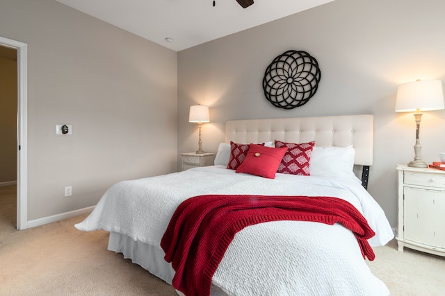 beige bedroom white a white bed and red accent pillows